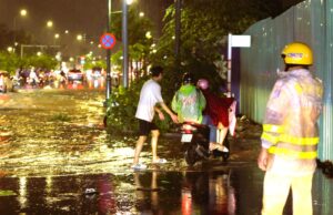 Sài Gòn mưa đêm, thanh niên dừng xe dẫn người đi đường tránh ngập